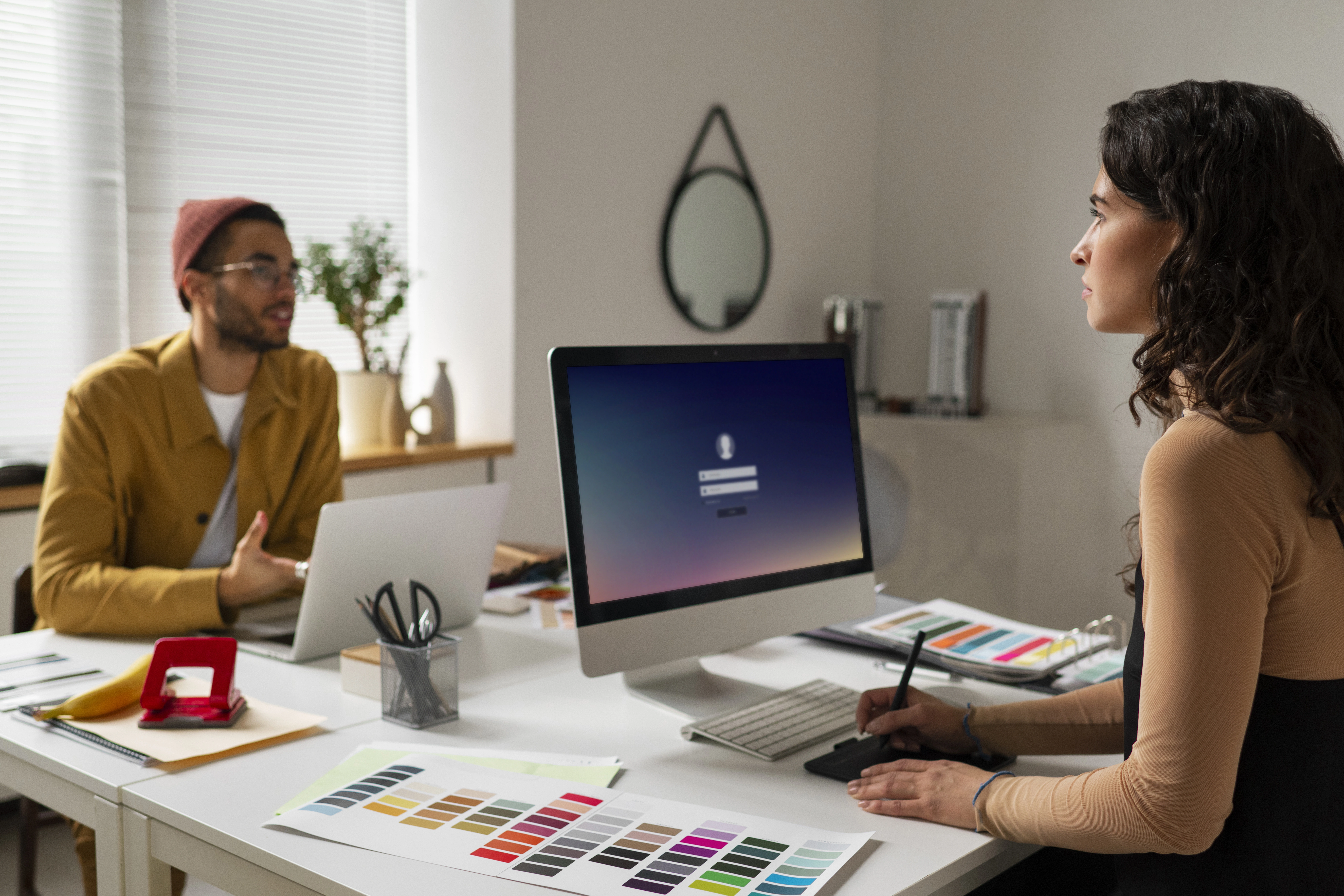 Web developers collaborating in a modern office, reviewing UI design elements and color palettes on desktop computers