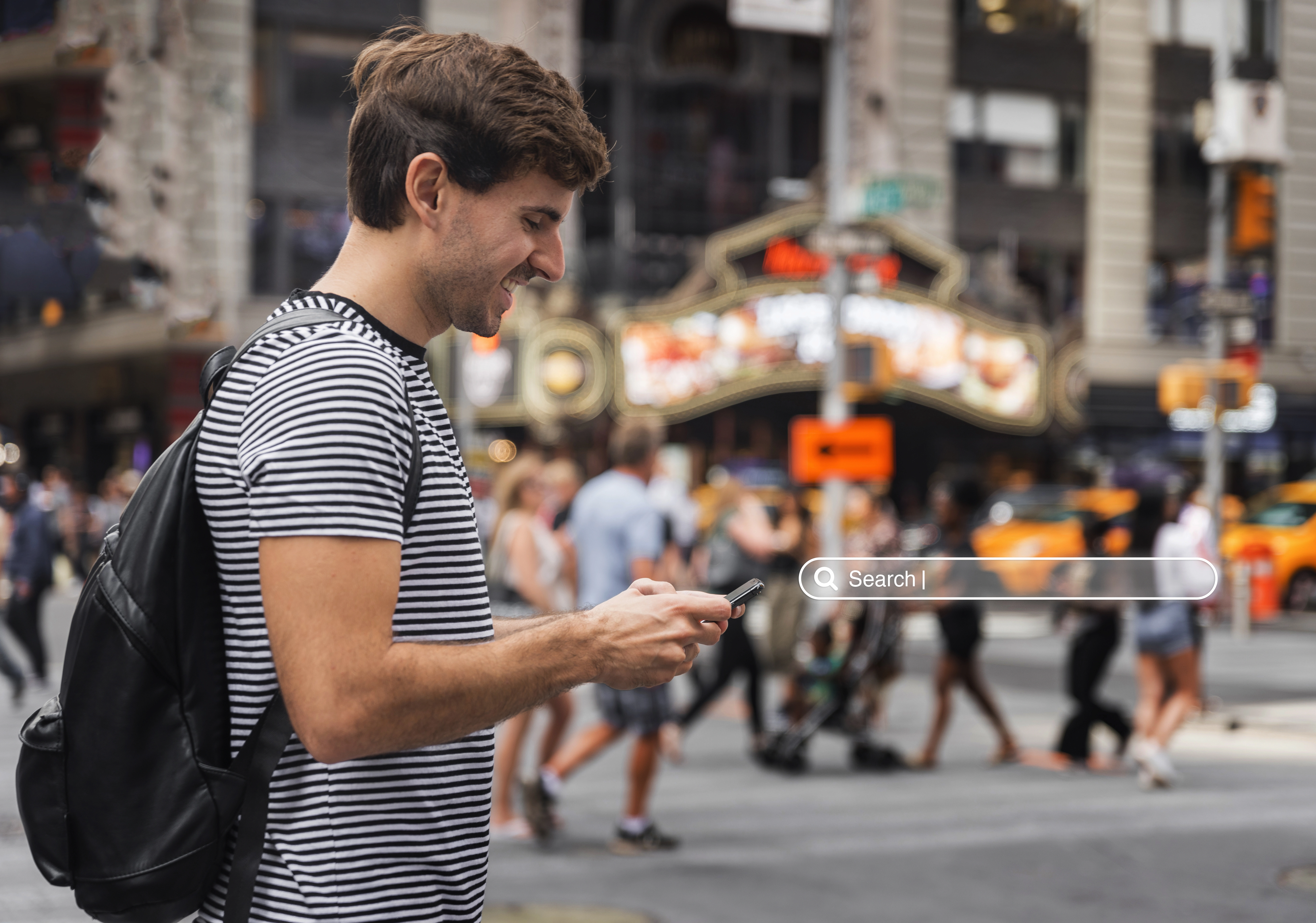 Young man using a mobile phone on a busy Chicago street, representing the importance of mobile-friendly eCommerce website design in Chicago for attracting on-the-go shoppers